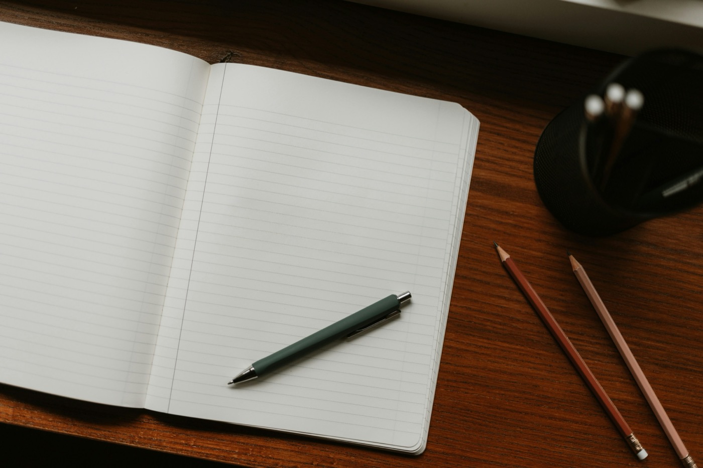 An open notebook and pencils on a wooden desk